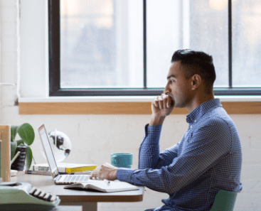 Man sitting at desk looking at laptop